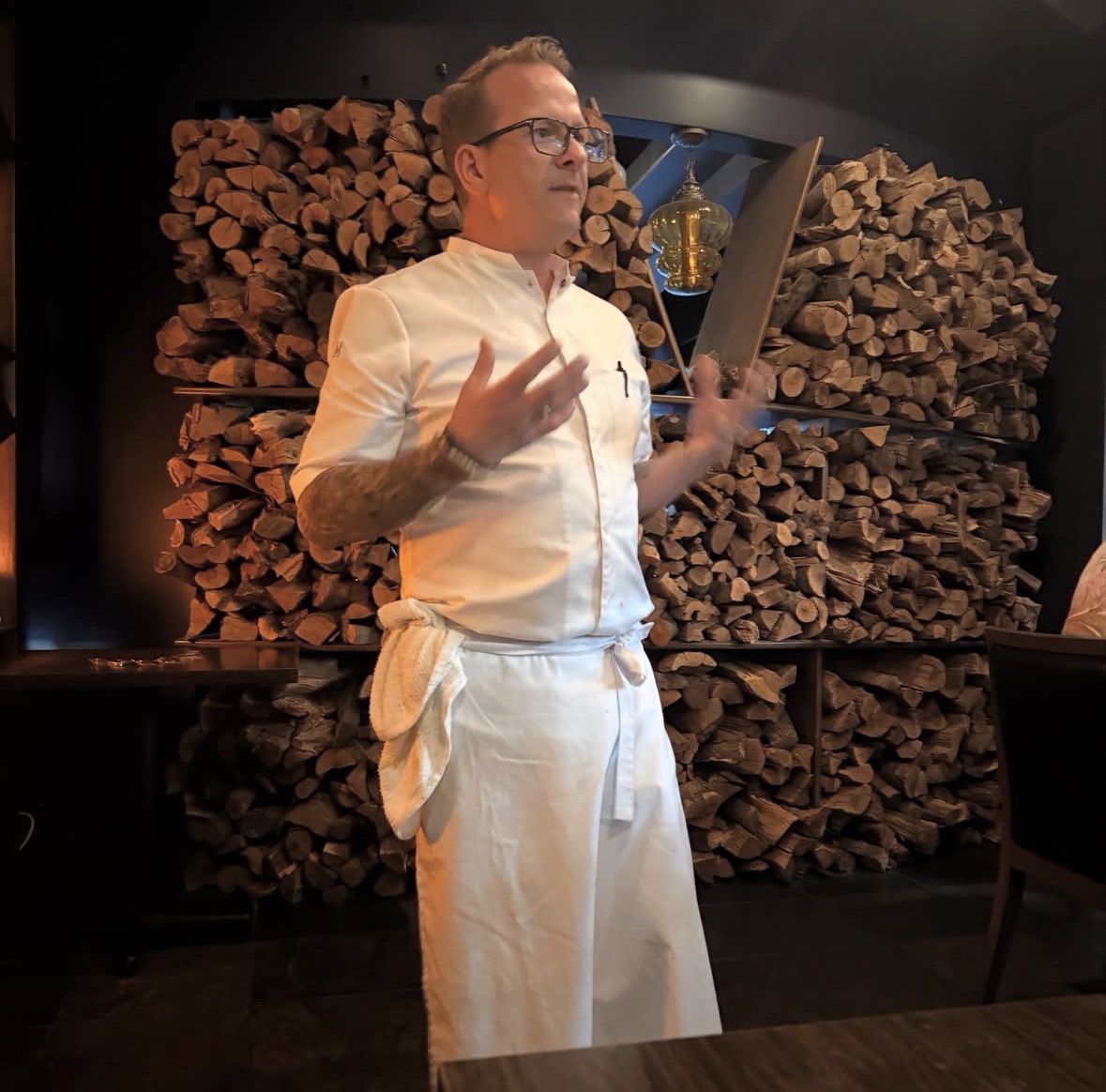 Chef greeting guests beside the wood-fired hearth