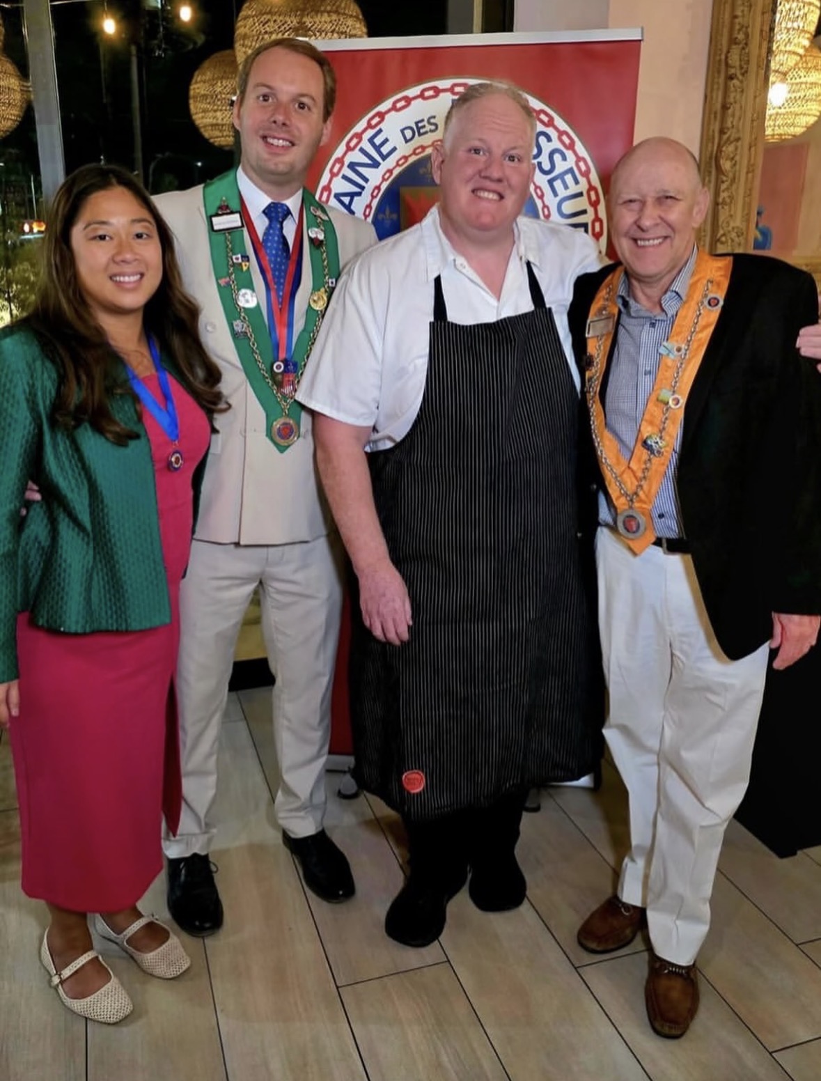 Bailliage officers with the guest chef at the Chaîne banner